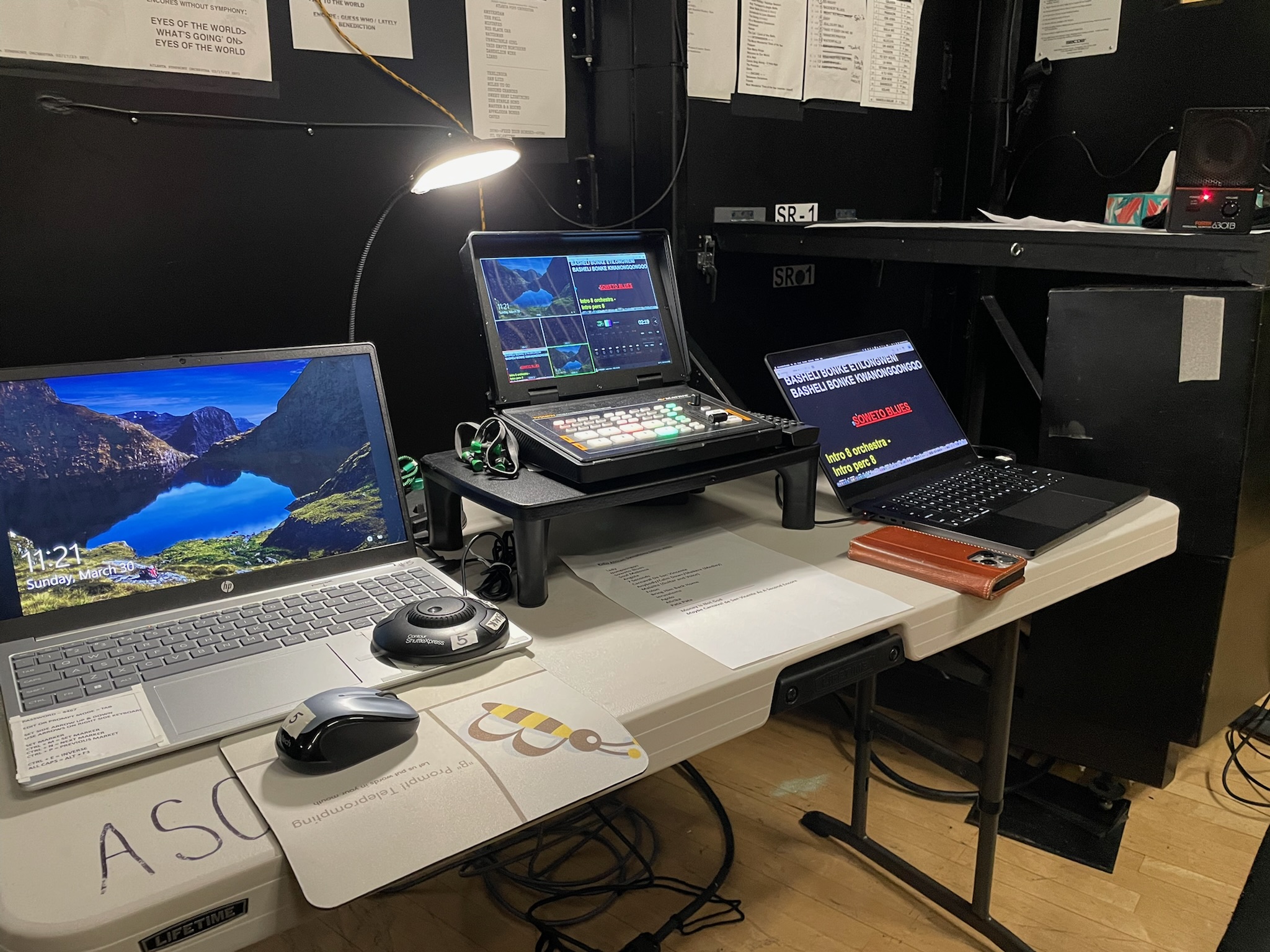 B Prompt control desk with laptops, scripts, and a teleprompter controller backstage
