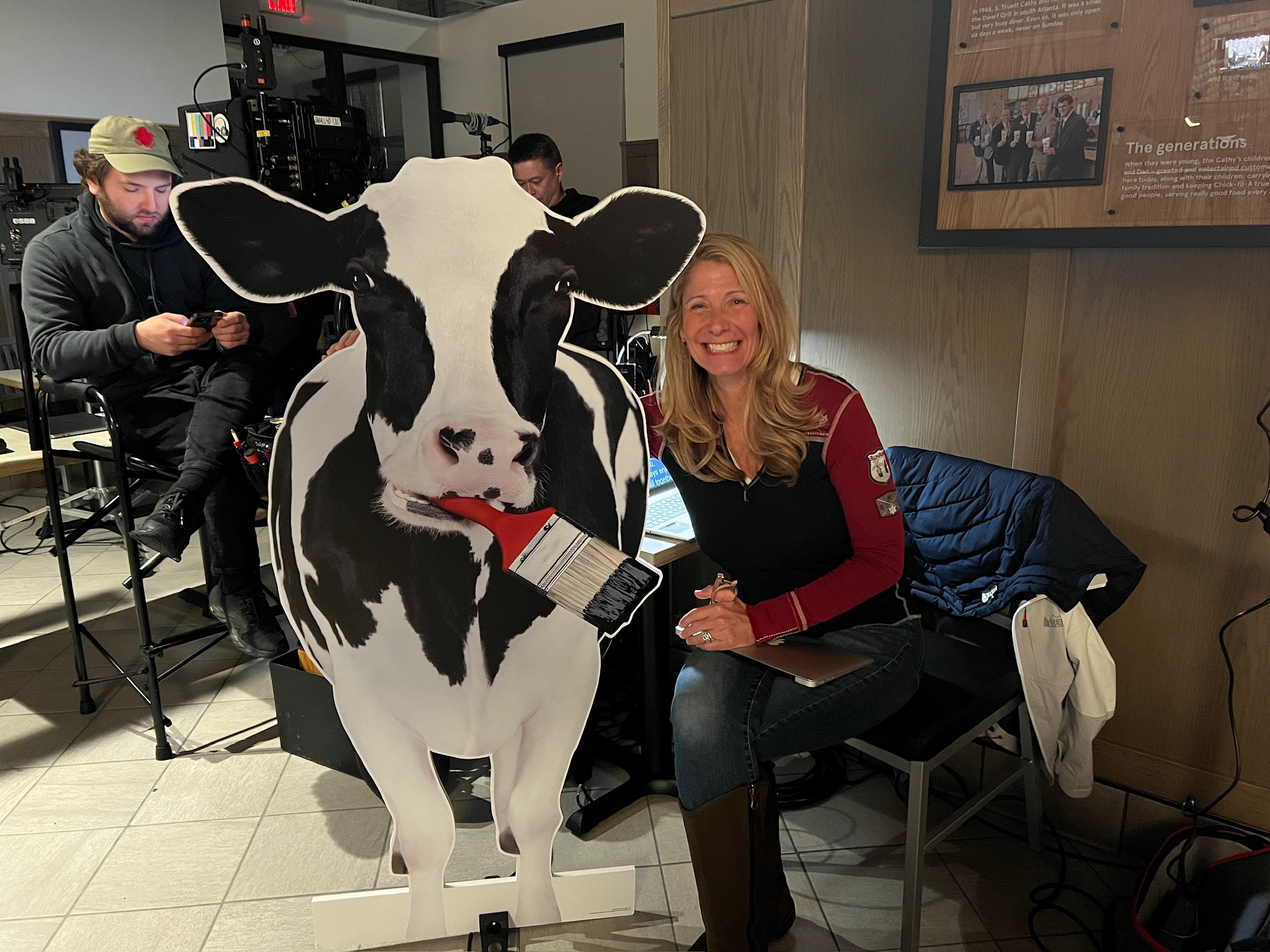 B Prompt operator on a production set beside a life-size cow cutout